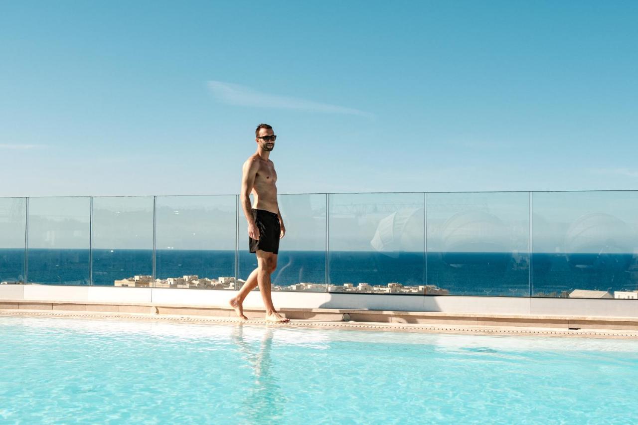 Hotel Hyatt Regency Malta San Giuliano Esterno foto A man walking on the edge of a swimming pool